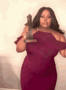 a woman in a purple dress is holding a trophy in her hands