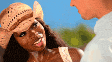 a woman wearing a cowboy hat smiles at a man in a white shirt