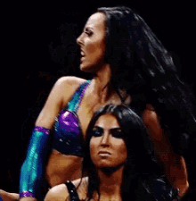 a couple of women standing next to each other with one wearing a purple top