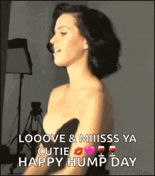 a woman in a black dress is standing in front of a tripod and says `` looove & miss ya cutie happy hump day ''