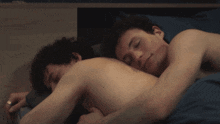 two shirtless men are laying on a bed with their eyes closed