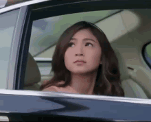 a woman is looking out the window of a car .