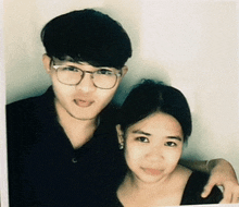 a man and a woman are posing for a picture and the man is wearing glasses