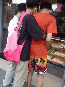 three men standing in front of a dunkin donuts display case