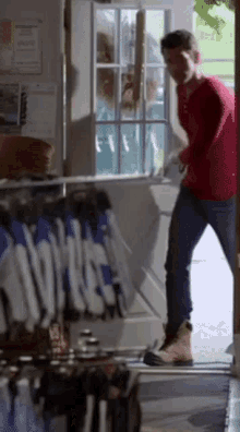 a man in a red shirt is standing in front of a glass door
