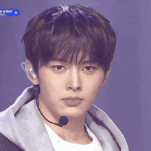 a close up of a young man wearing a microphone and earbuds