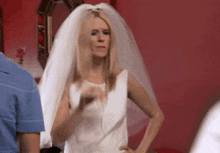 a woman in a wedding dress with a veil is pointing