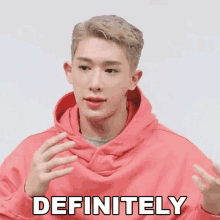 a man in a pink hoodie says definitely with his hands out