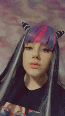 a close up of a woman 's face with pink and blue hair blowing a kiss .