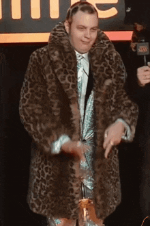 a man wearing a leopard print fur coat is holding a trophy