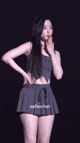 a woman wearing a pleated skirt and a crop top with the words aefearnot on the bottom right