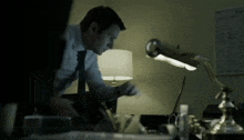 a man in a suit and tie is sitting at a desk in front of a lamp with the word one on it
