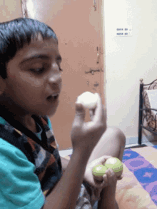 a young boy is sitting on a bed eating a sandwich