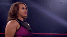 a woman in a purple top stands in a ring with the letters fite on the bottom