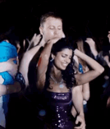 a woman in a purple dress is dancing in a crowd