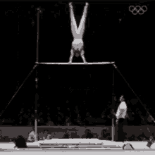 a female gymnast is doing a handstand on a bar .
