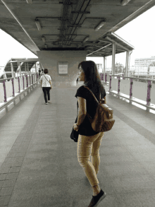 a woman walking across a bridge with a sign that says ' bangkok ' on it