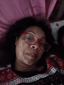 a woman wearing red glasses is laying down on a bed