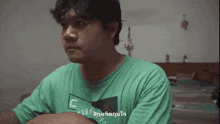 a man in a green shirt is making a funny face