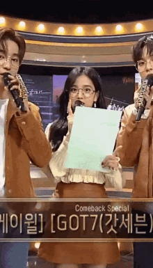 a girl with glasses is holding a piece of paper in front of a sign that says comeback special got7