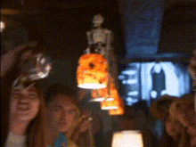 a blurry picture of a group of people standing around a table with a lamp hanging from the ceiling