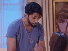 a man with a beard wearing a necklace is standing next to a woman .