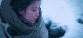 a woman wearing a scarf around her neck looks down in the snow