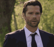 a man with a beard wearing a suit and tie looks surprised