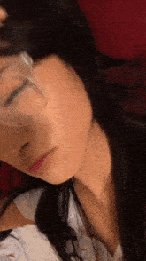 a woman wearing glasses and a white shirt is laying down with her eyes closed