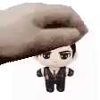 a hand is holding a stuffed doll of a man in a suit on top of his head .