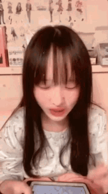 a girl with long hair and bangs is holding a tablet