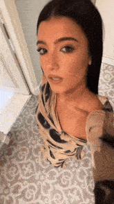 a woman taking a selfie in a bathroom with a patterned floor