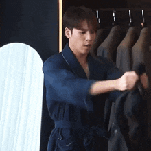 a man in a blue robe is standing in front of a mirror holding a jacket