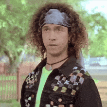 a man with curly hair is wearing a headband and a choker