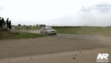 a car is driving down a dirt road with a nr logo on the bottom