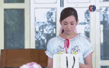 a woman in a blue shirt is holding a white bag with the number 3 on it