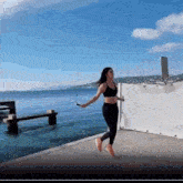 a woman is jumping a jump rope in front of the ocean