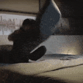 a man is sitting on a bed throwing a pillow in the air