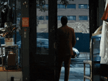 a man in a red suit is standing in front of a door that has a sign on it that says push button to exit
