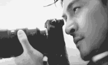 a man is holding a camera in his hand and looking through it .