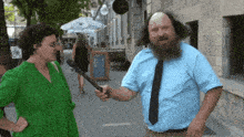 a man in a blue shirt and tie is talking to a woman