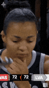 a female basketball player looks at the scoreboard which says 72-72