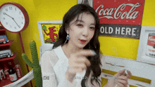a woman in front of a coca cola old here sign
