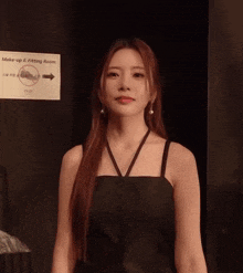 a woman stands in front of a sign that says make-up and fitting room