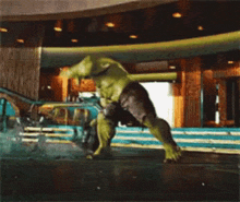 the hulk is standing on one leg in front of a waterfall in a building .