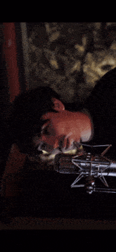 a man is laying down in front of a microphone with his eyes closed