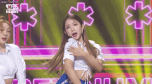 a woman is standing on a stage with her hands on her chest and a microphone .