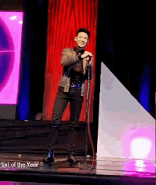a man singing into a microphone on a stage with the words artist of the year below him