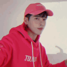 a young man wearing a pink hat and a red hoodie that says tune on it