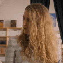 a woman with long blonde curly hair is wearing a striped shirt